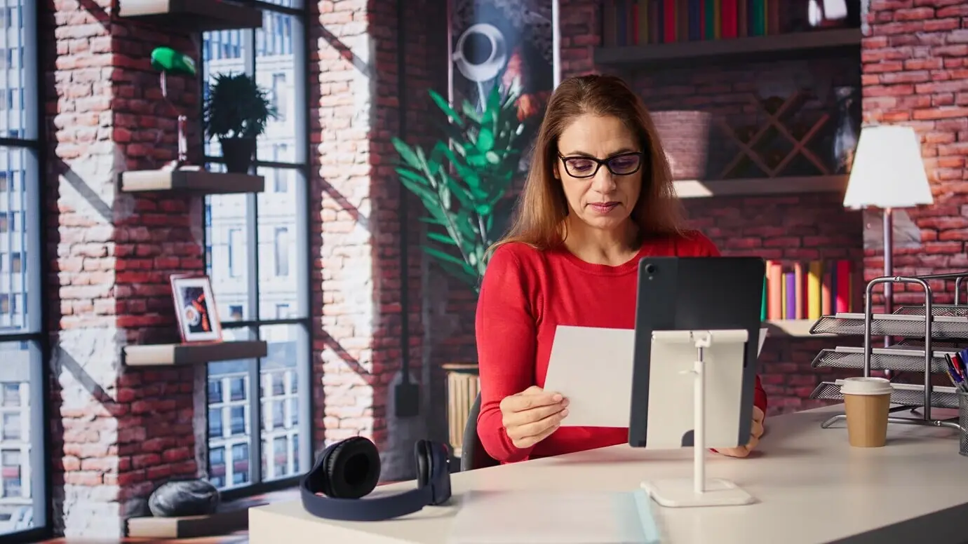 Selbstsichere, gut gelaunte Sprecherin, die Kolleginnen und Kollegen in einer Videobesprechung begrüßt.